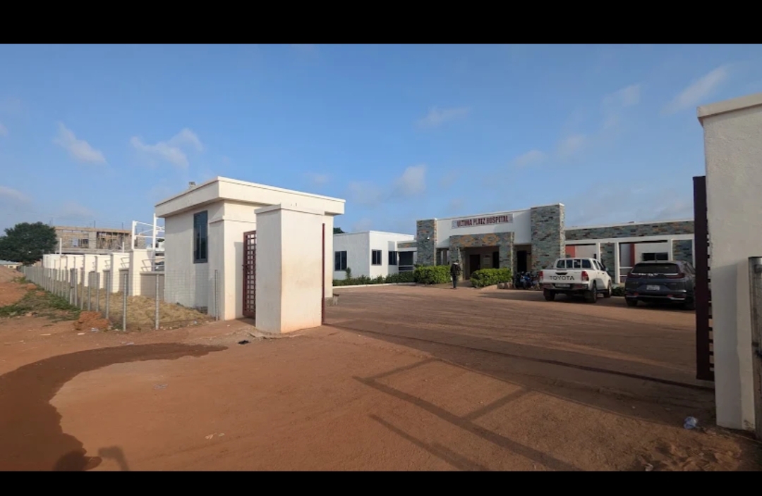 The gated entrance and forecourt of Ultima Platz Hospital seen from the access road.